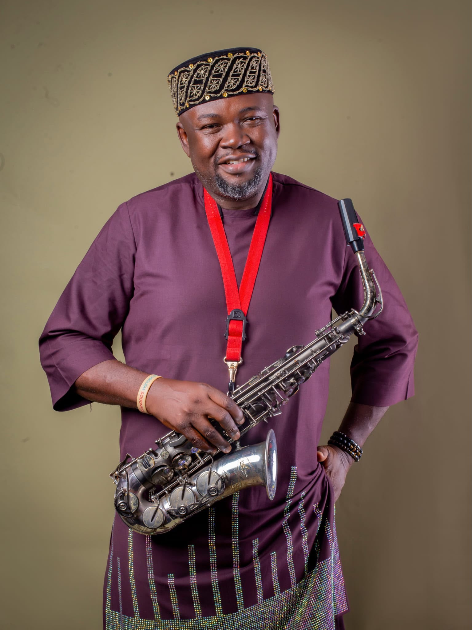 Burgundy agbada holding saxophone